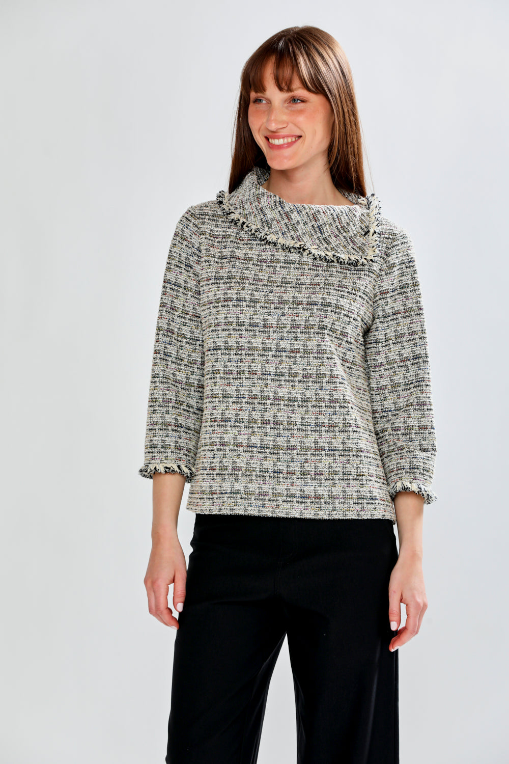 Woman wearing a patterned blouse with fringe collar against a white background