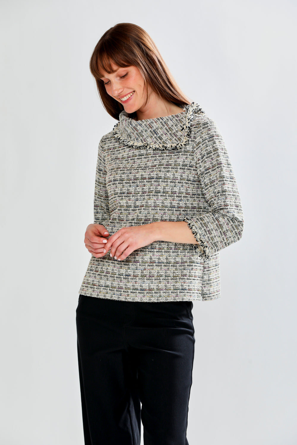 Woman wearing a patterned blouse with fringe collar against a white background