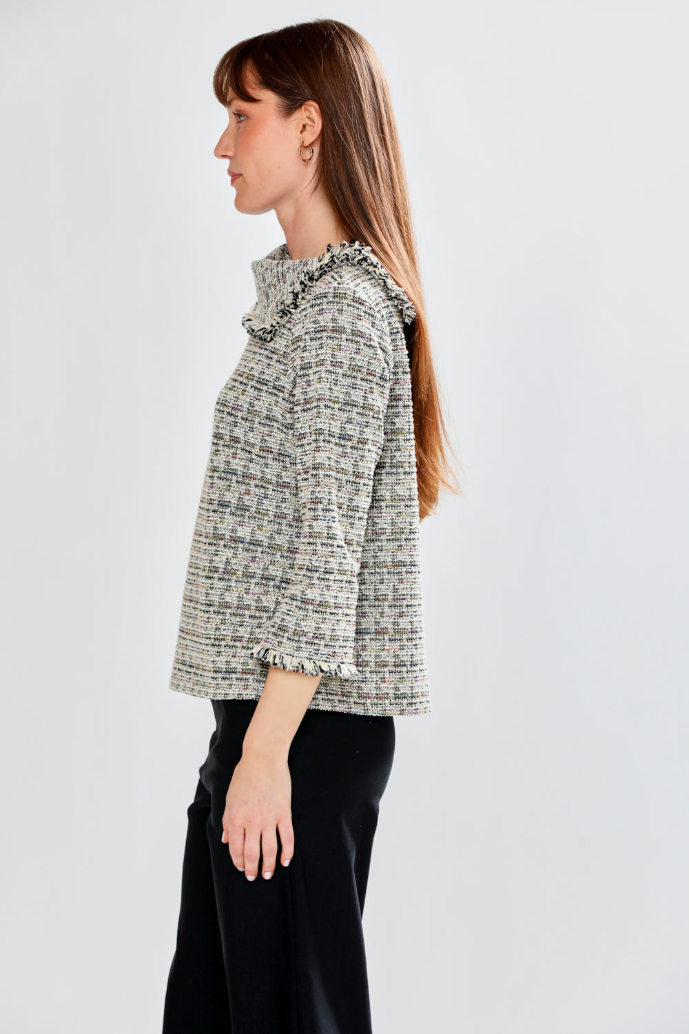 Woman wearing a patterned blouse with fringe collar against a white background