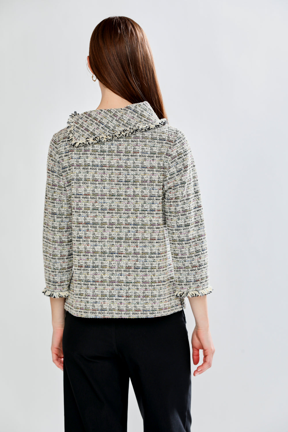 Woman wearing a patterned blouse with fringe collar against a white background