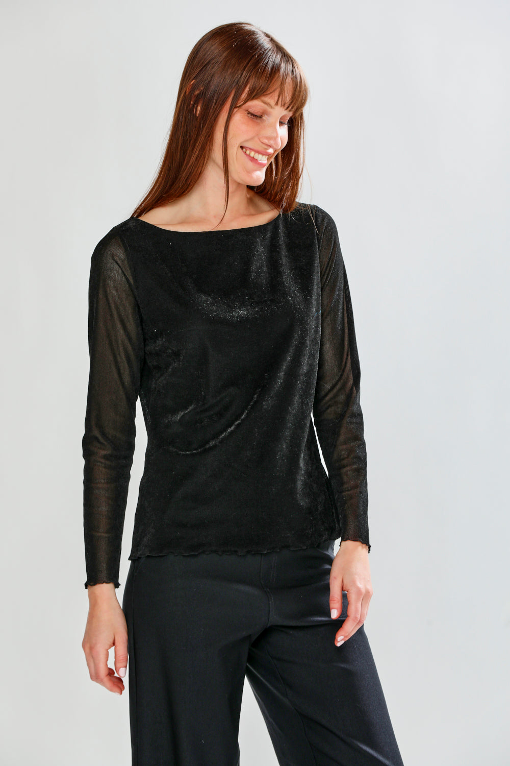 Woman wearing a black long-sleeve top and black pants on a light gray background