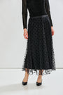 Person wearing a black polka dot tulle skirt with a plain background