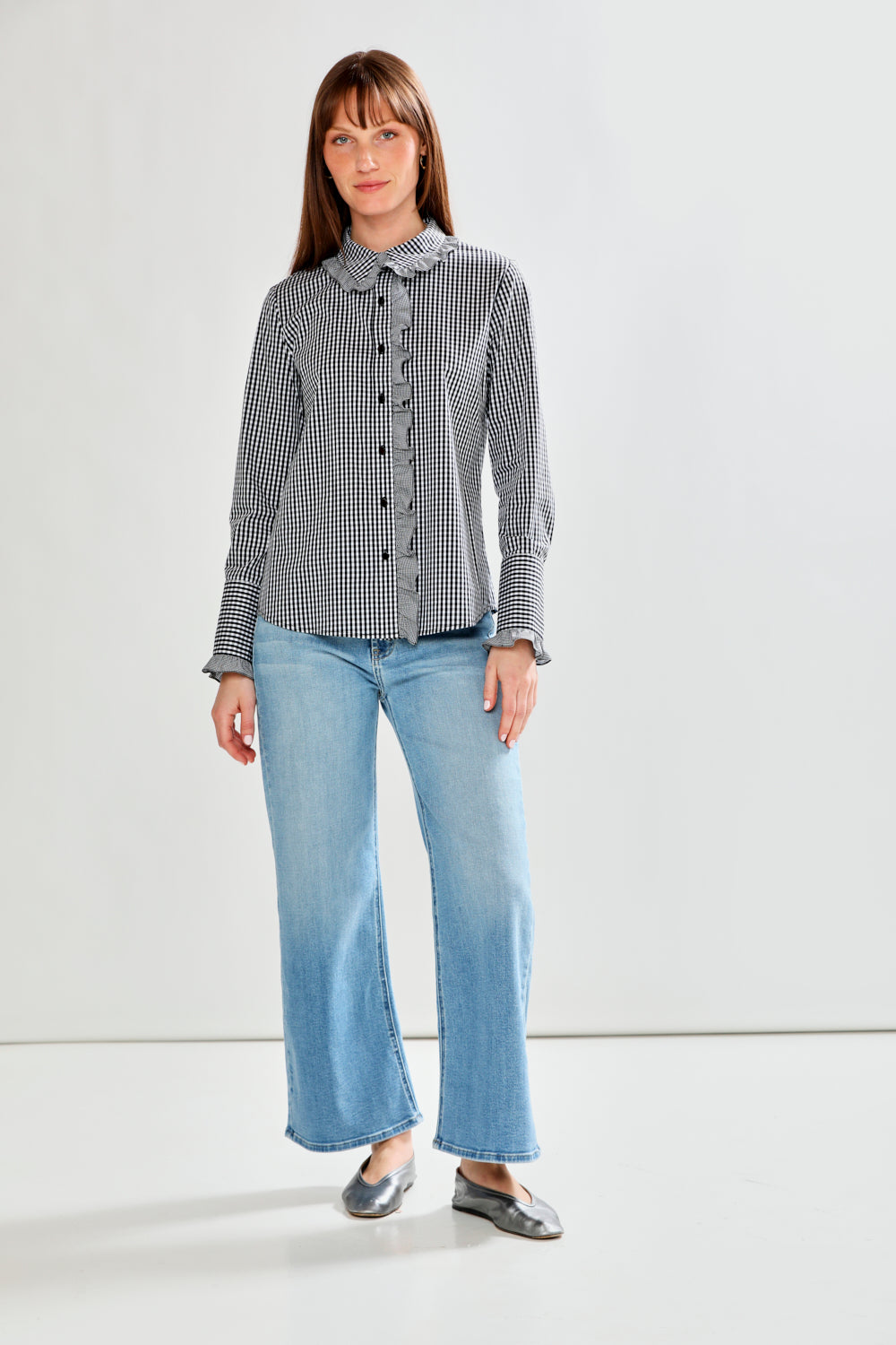 Woman wearing a checkered shirt and blue jeans against a white background