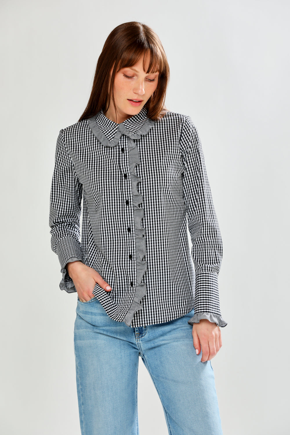 Woman wearing a checkered shirt and jeans on a plain background