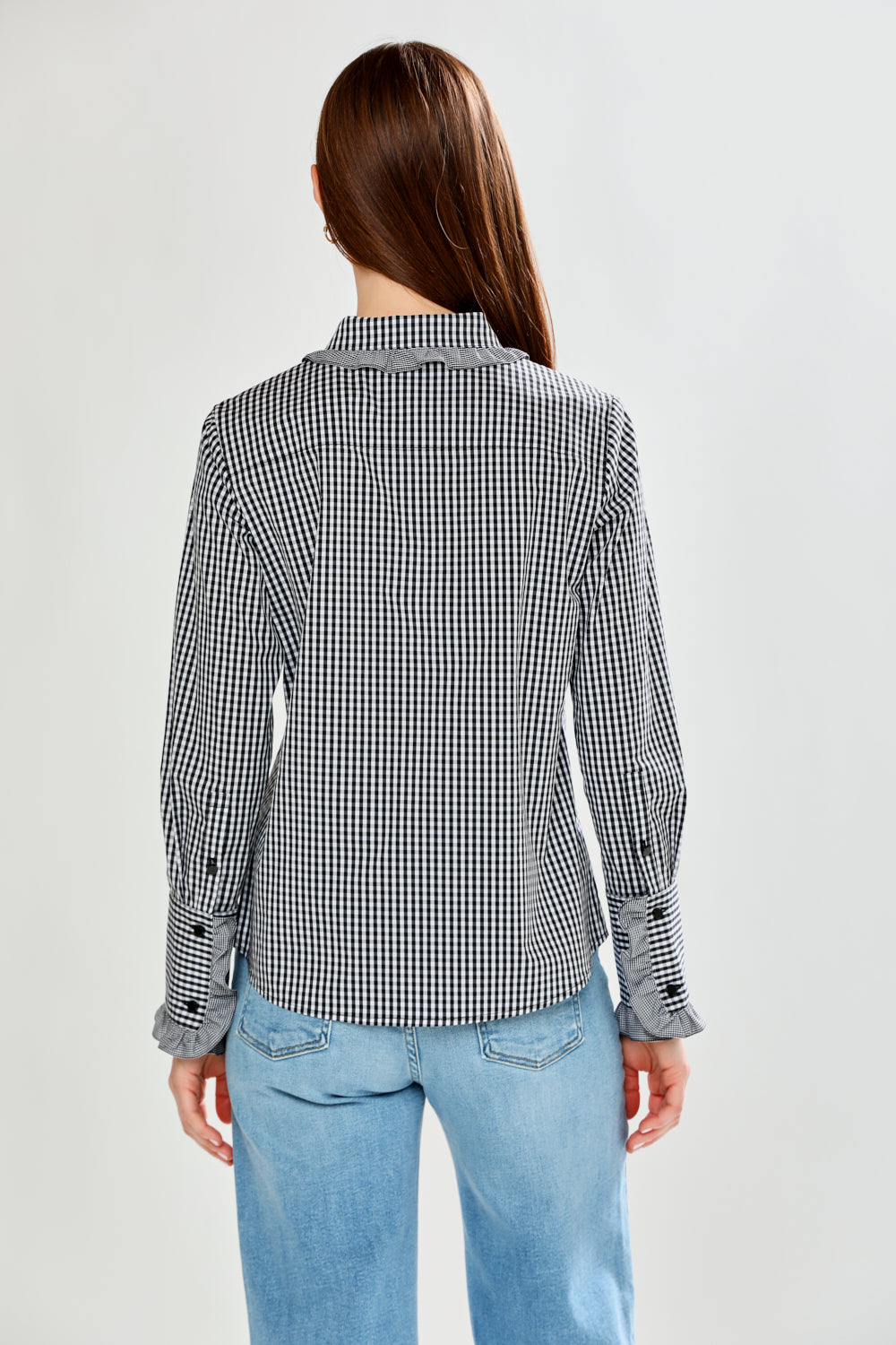 Person wearing a checkered blazer and light blue jeans on a white background