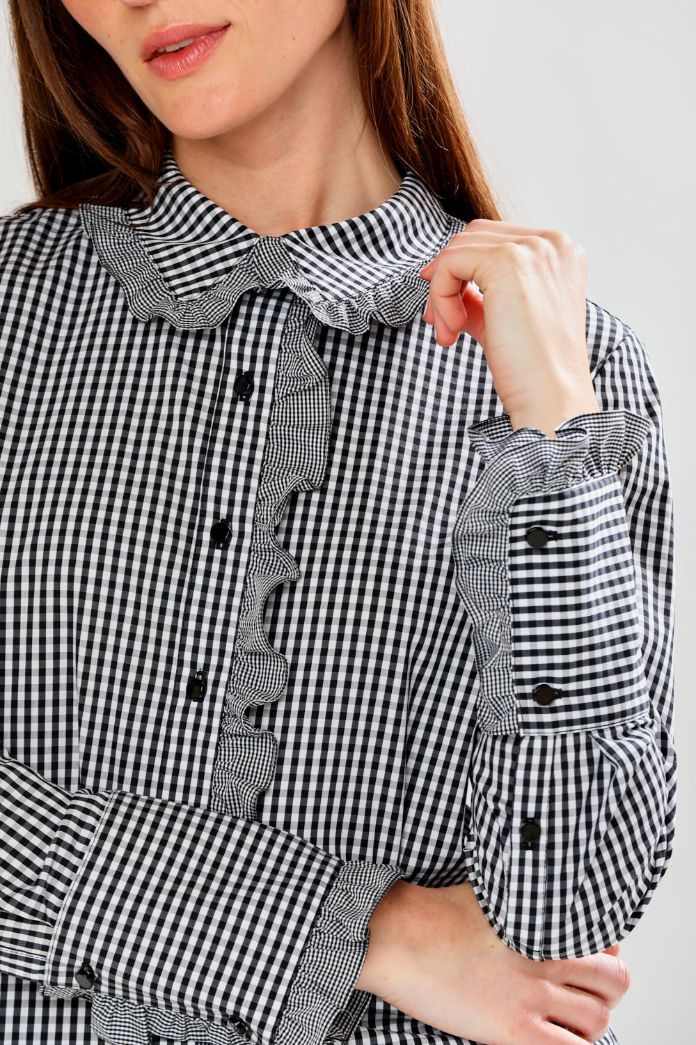 Black and white checkered blouse with ruffled details on a plain background