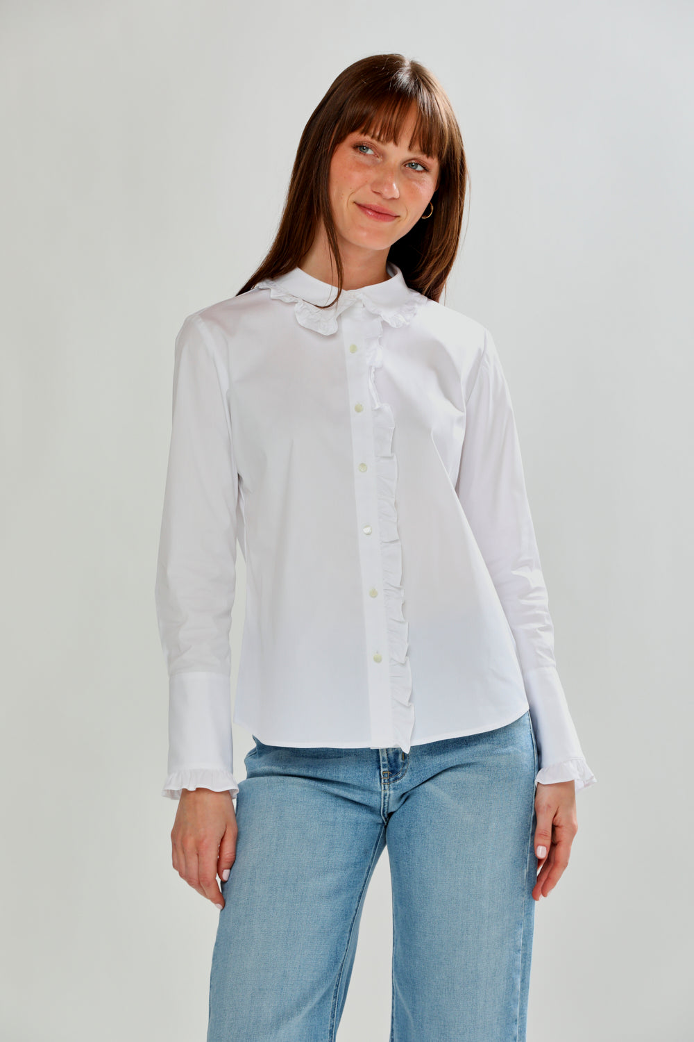 Woman wearing a white shirt and blue jeans on a plain background
