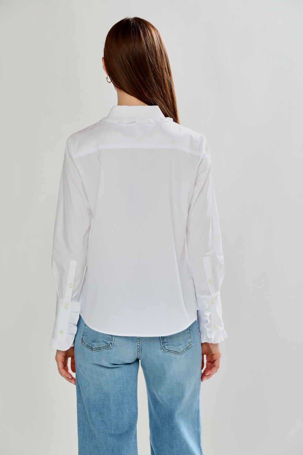 Person wearing a white shirt and blue jeans on a plain background