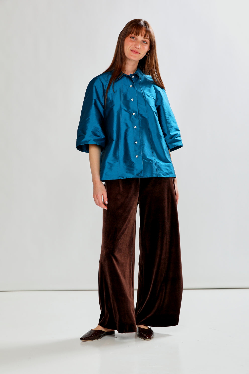 Woman wearing a blue shirt and brown pants on a white background