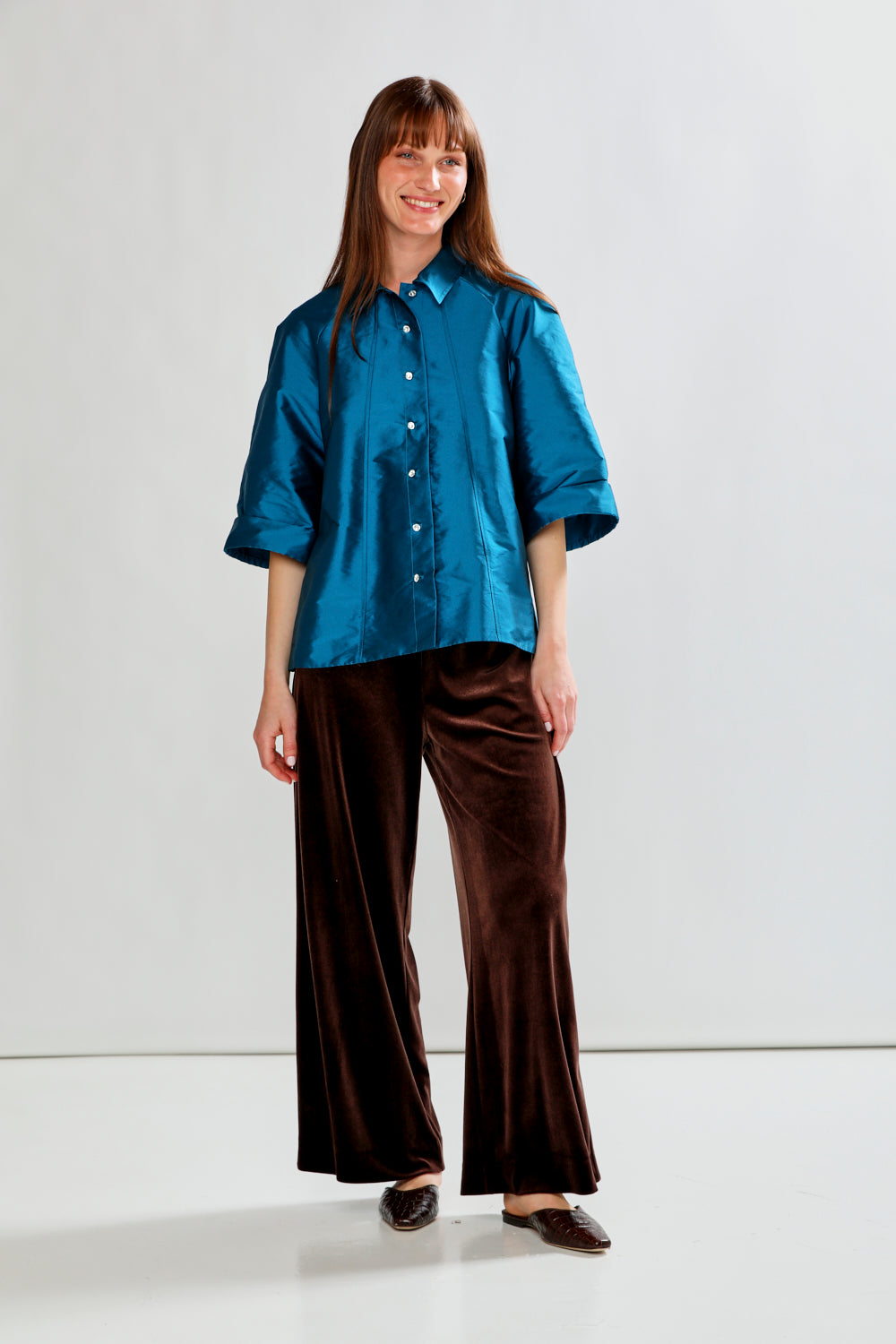 Woman wearing a blue shirt and brown pants on a white background