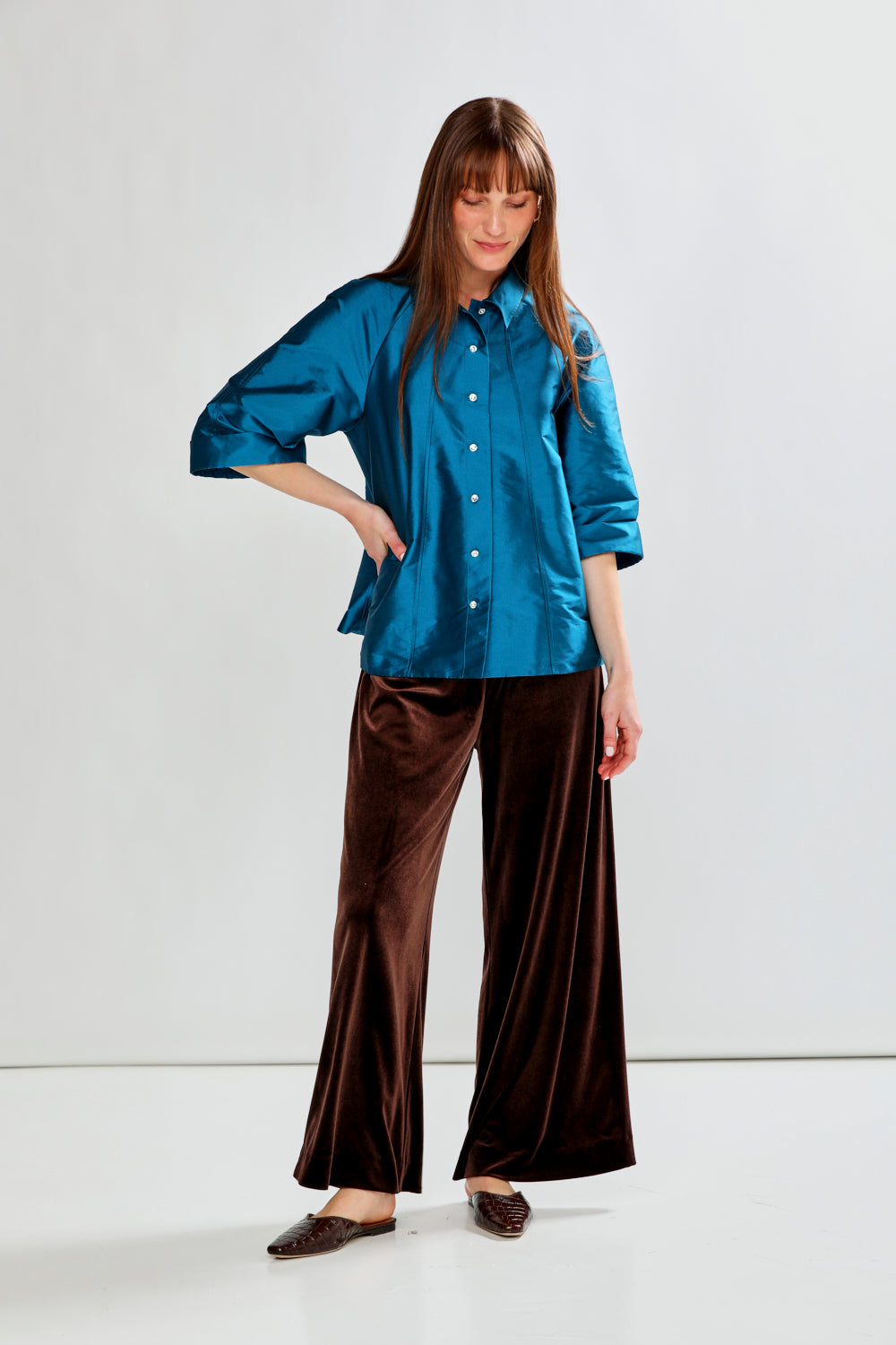 Woman wearing a blue shirt and brown pants on a white background