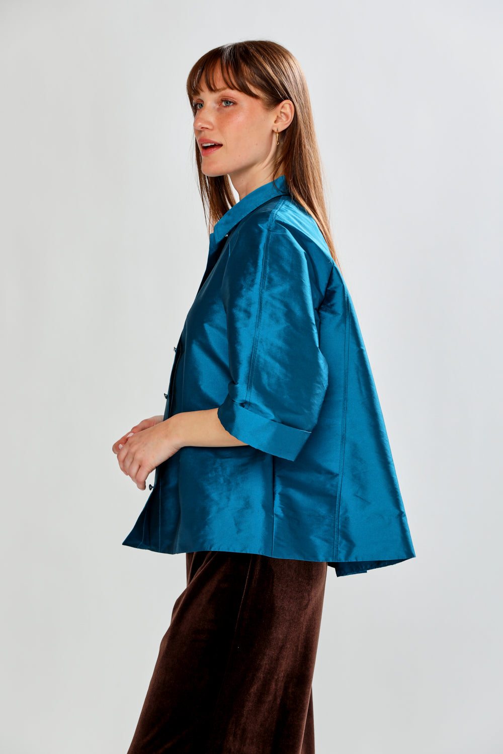 Woman wearing a blue jacket and brown pants on a white background