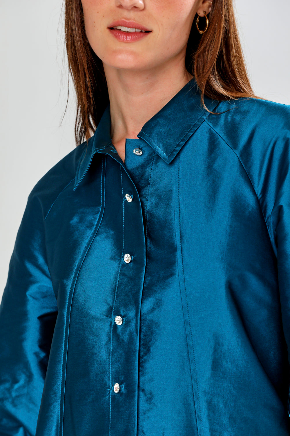 Blue satin shirt worn by a person on a white background