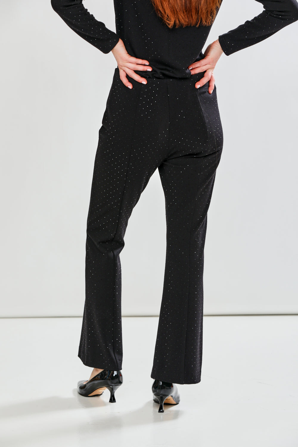Person wearing a black outfit with polka dots on a white background