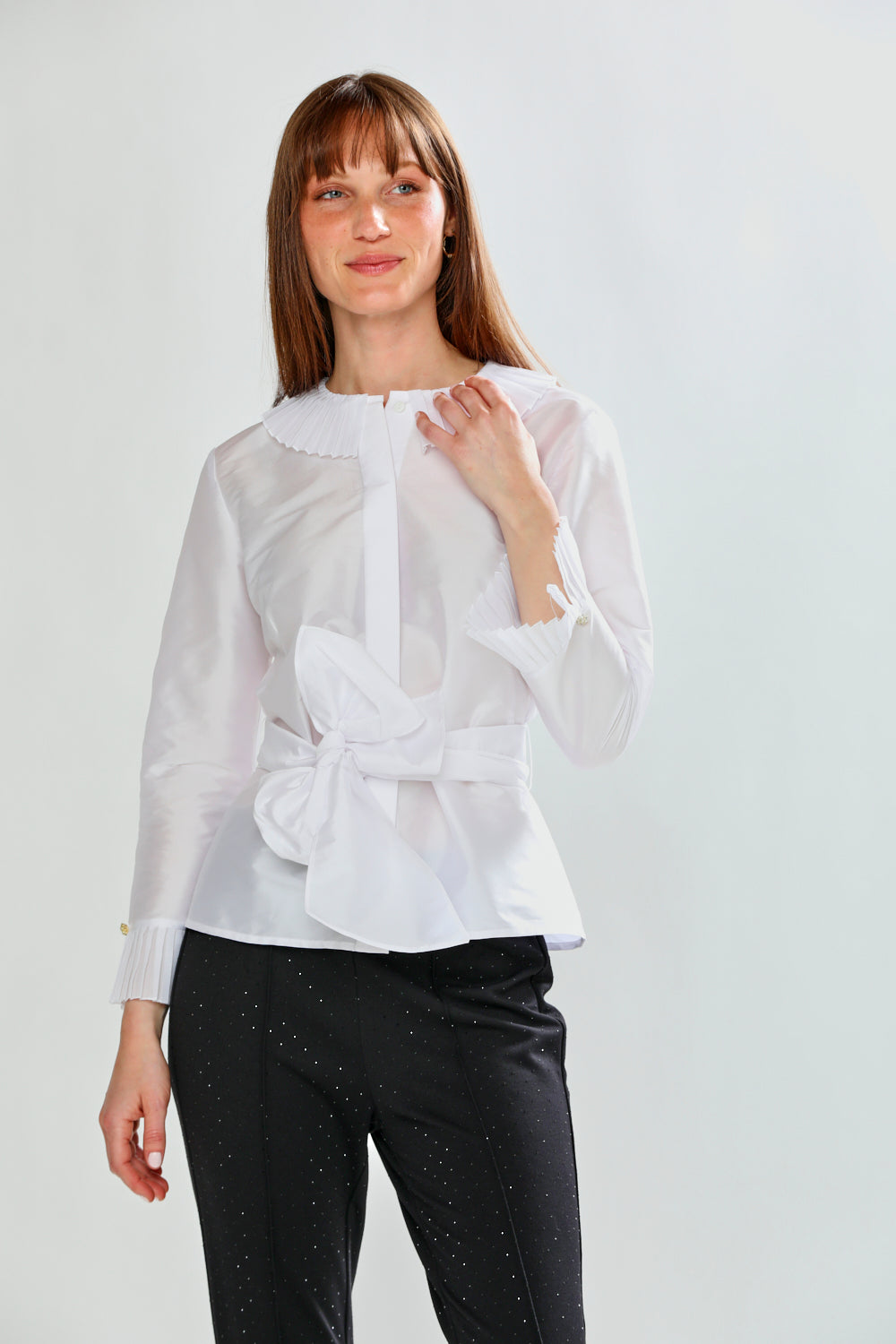Woman wearing a white blouse with a bow detail on a light gray background