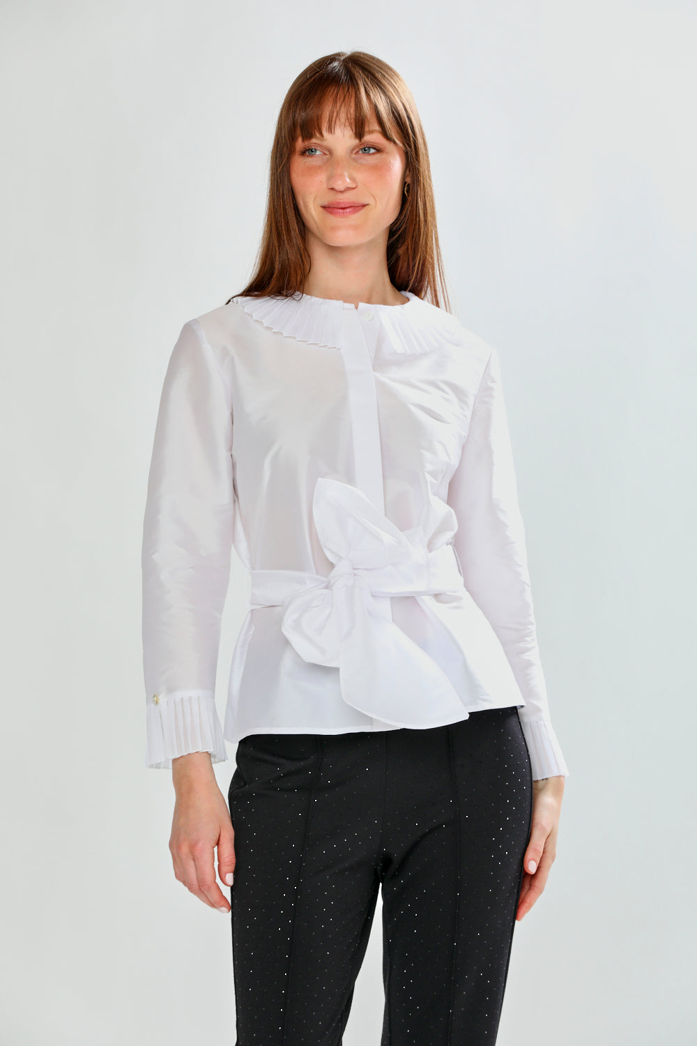 Woman wearing a white blouse with ruffled details on a light gray background