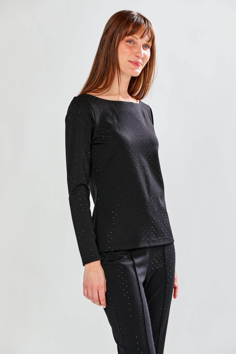 Woman wearing a black long-sleeve top and black pants on a light gray background
