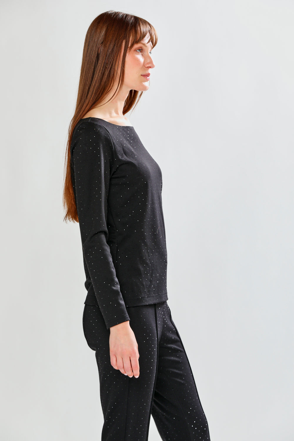 Woman wearing a black long-sleeve top and pants on a white background