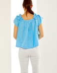 Woman in pacific blue ruffled top