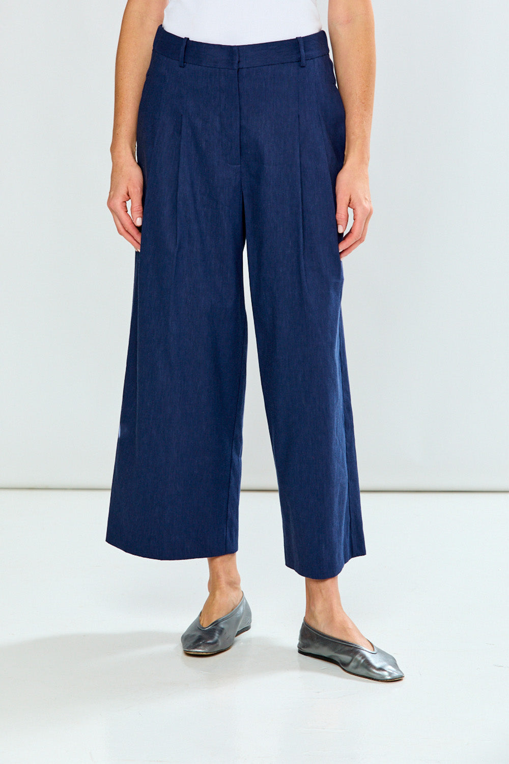 Person wearing navy blue wide-leg pants on a white background