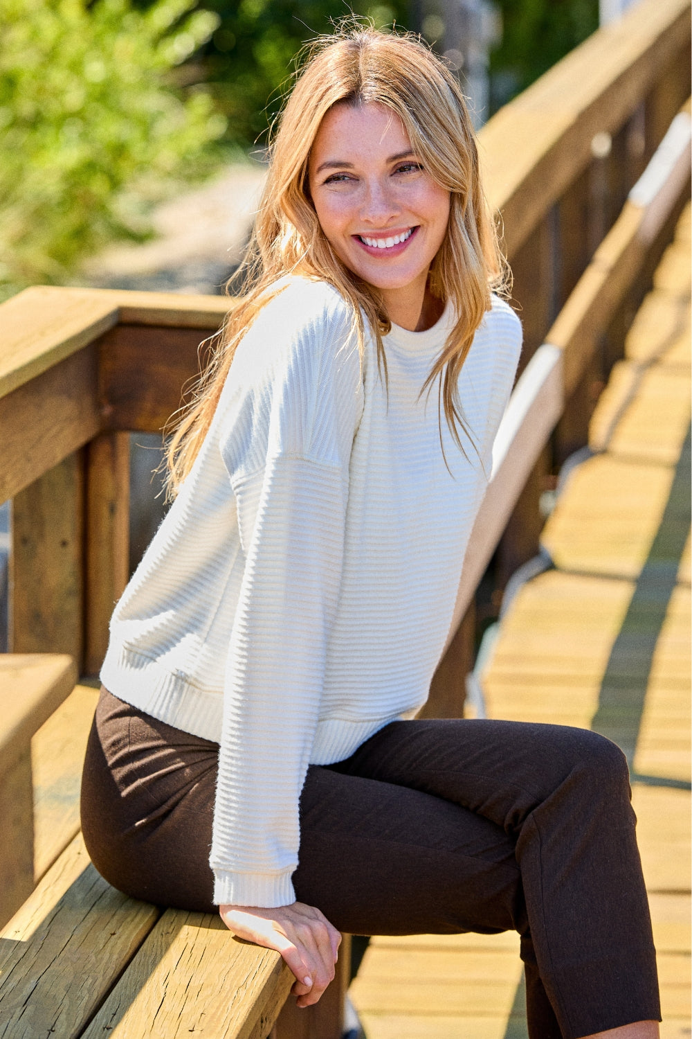 Woman in white sweater and brown pants 