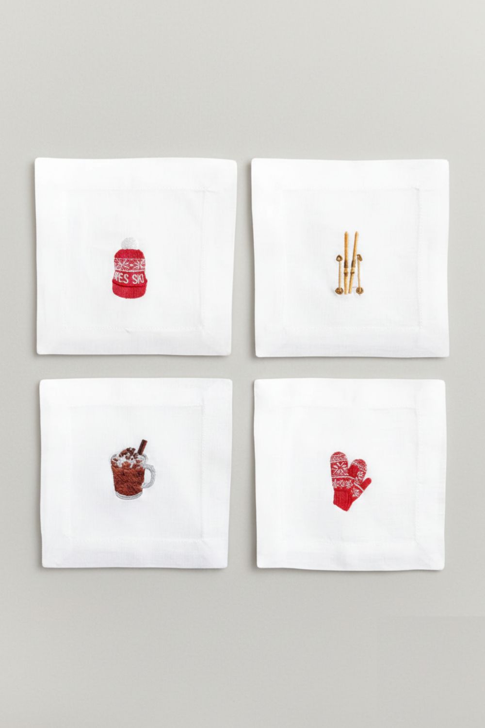 Four white napkins with red and gold designs on a gray background