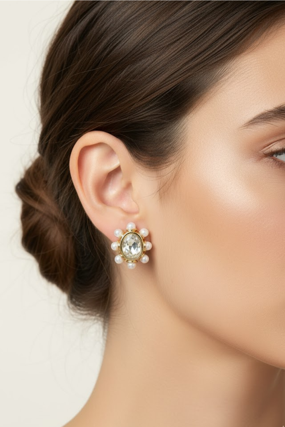 Close-up of a woman wearing a gold earring with a central gemstone and pearl-like accents.