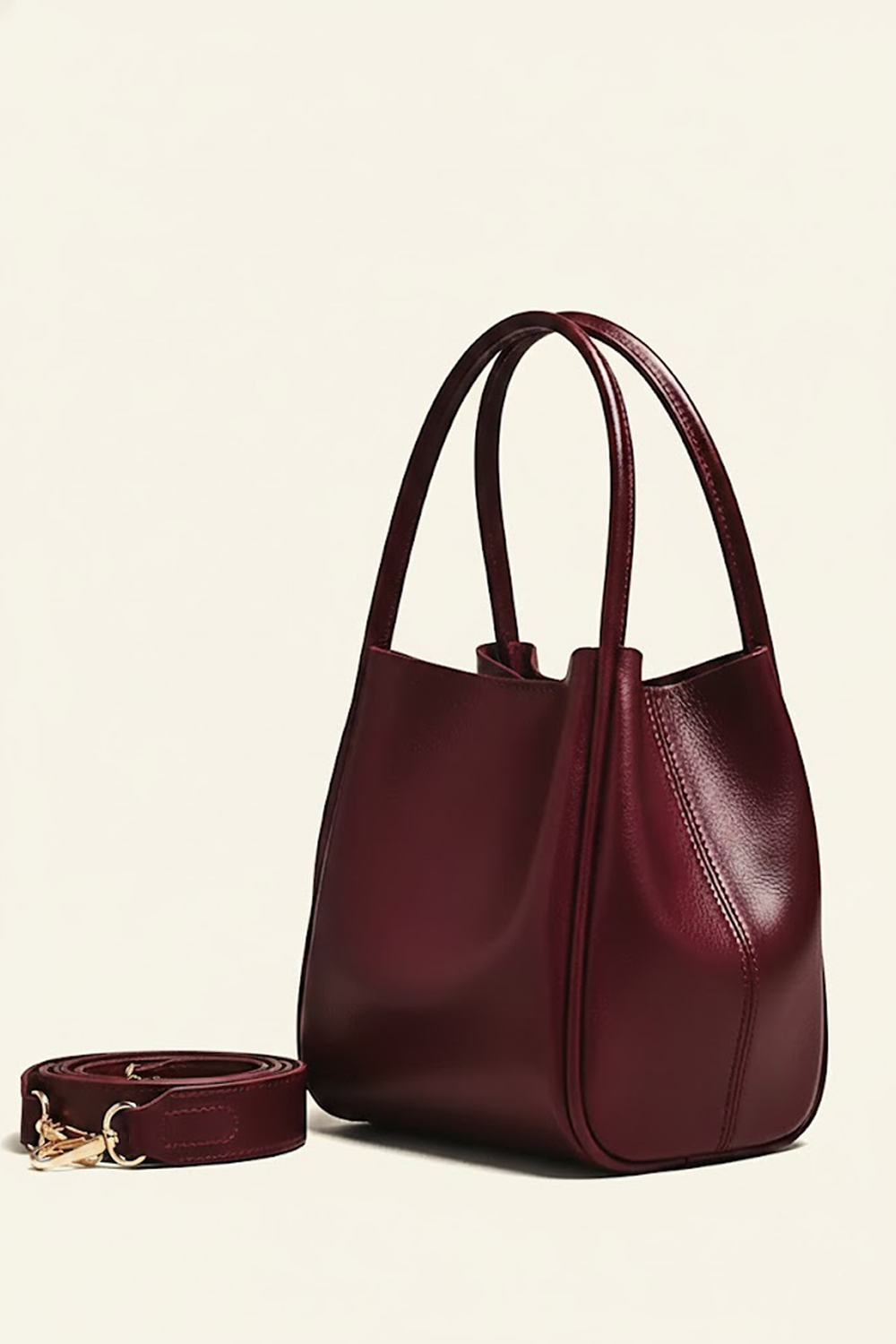 Burgundy handbag with matching strap on a beige background