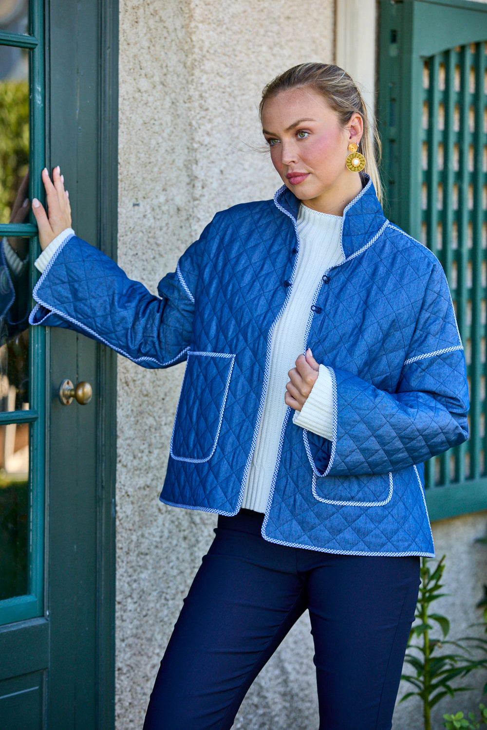 Woman wearing a blue quilted jacket standing outside a building.