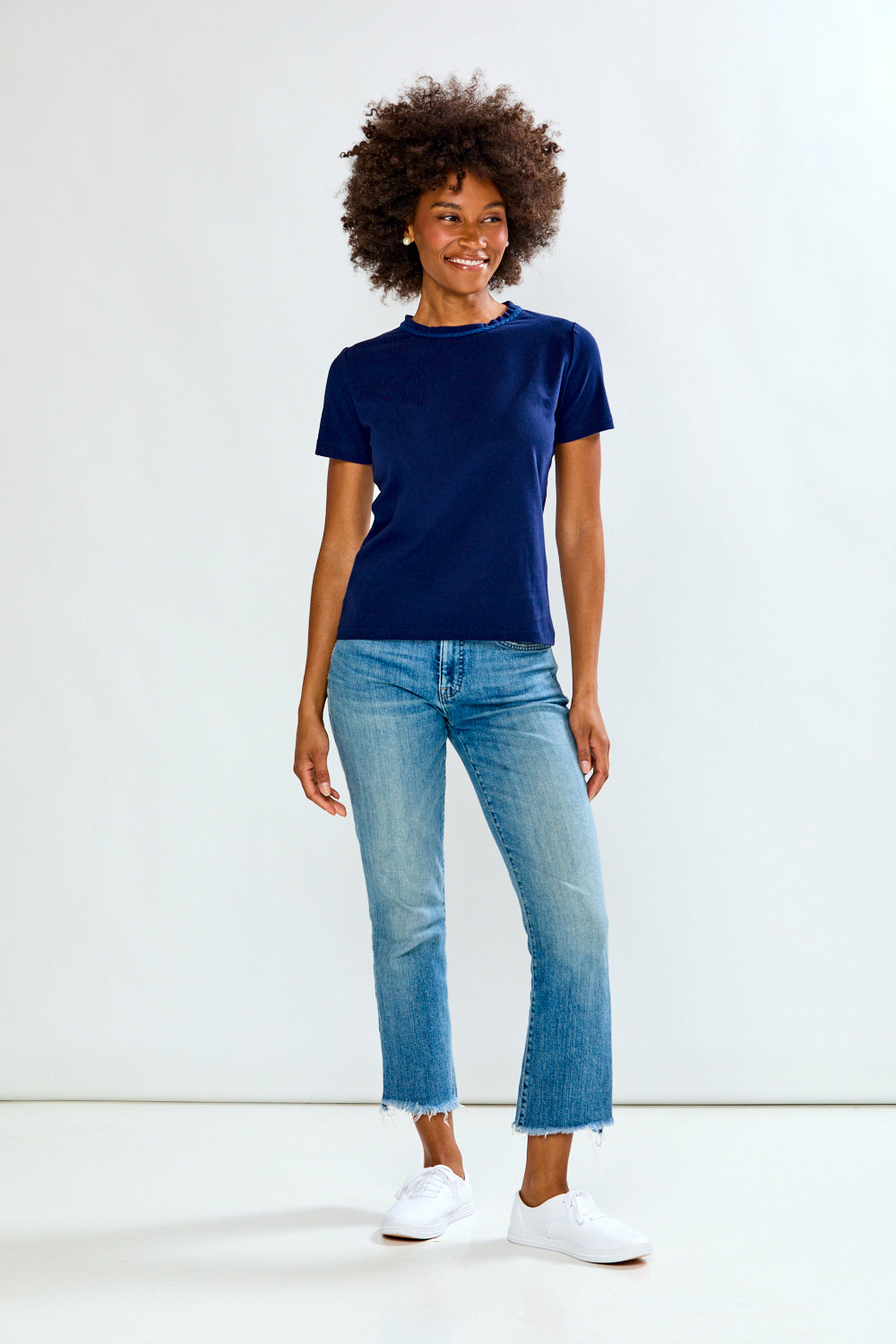Person wearing a navy t-shirt and light blue jeans on a white background