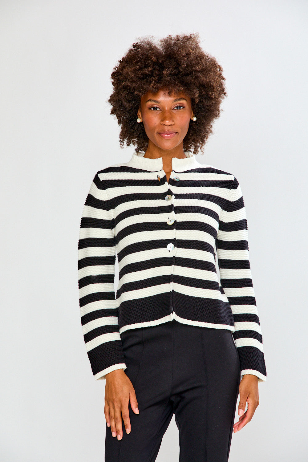 Woman wearing a black and white striped cardigan against a plain background