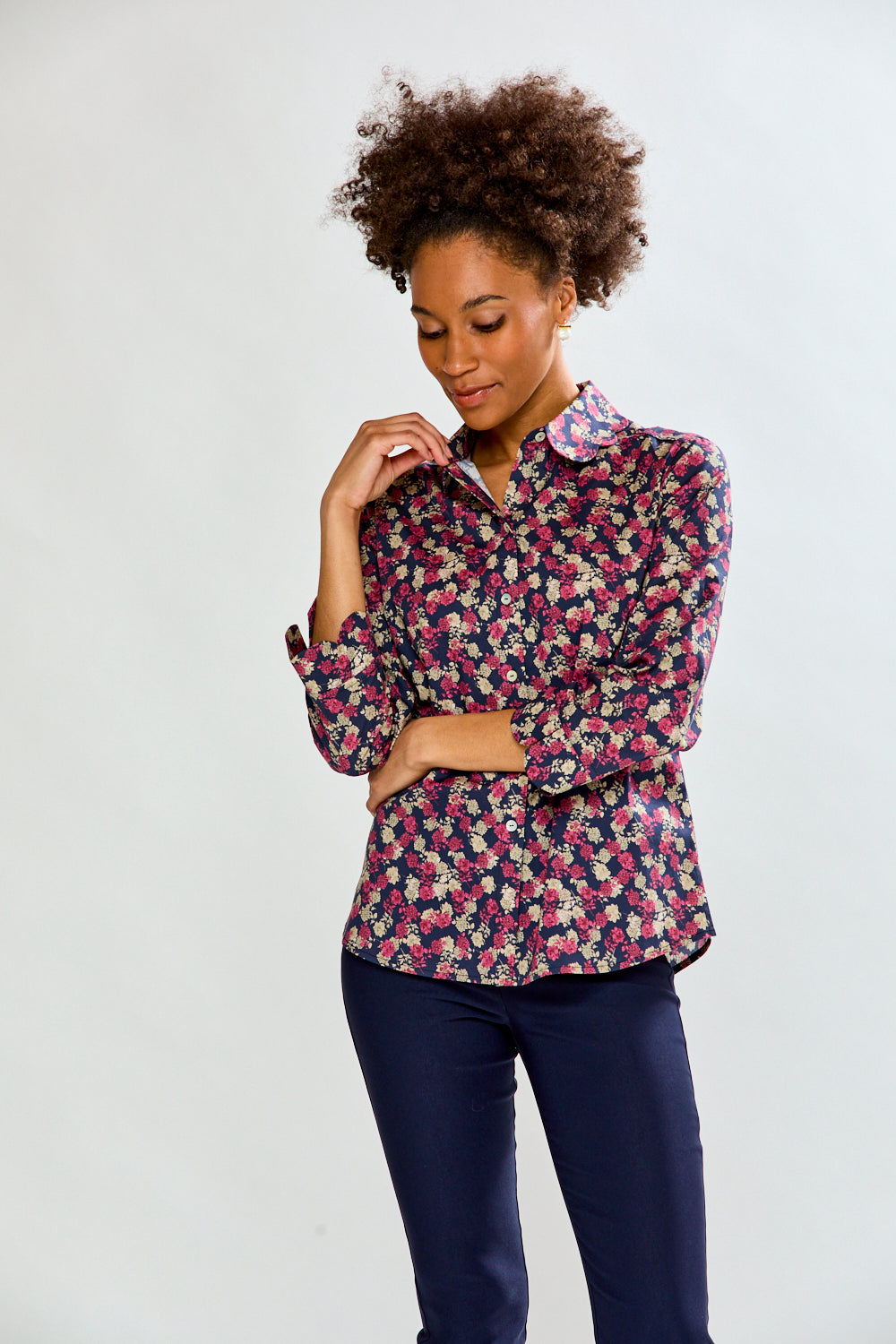 Woman wearing a floral shirt and dark pants on a white background