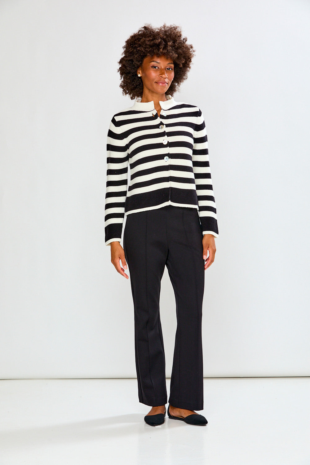 Woman wearing a black and white striped sweater and black pants on a white background