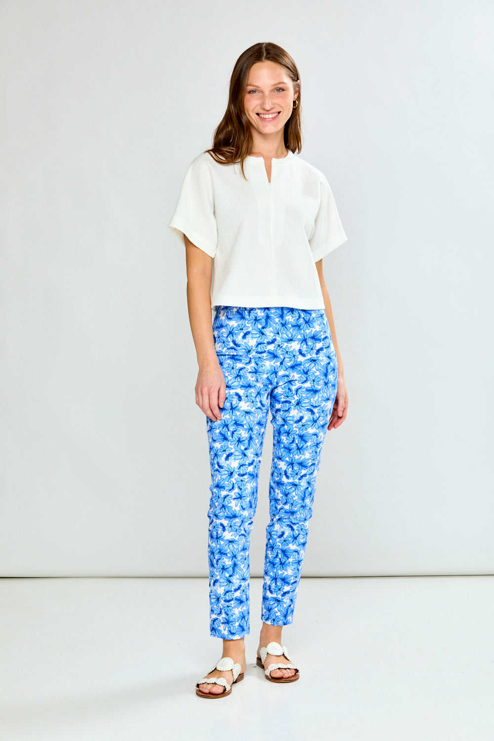 Woman wearing a white blouse and blue patterned pants on a white background