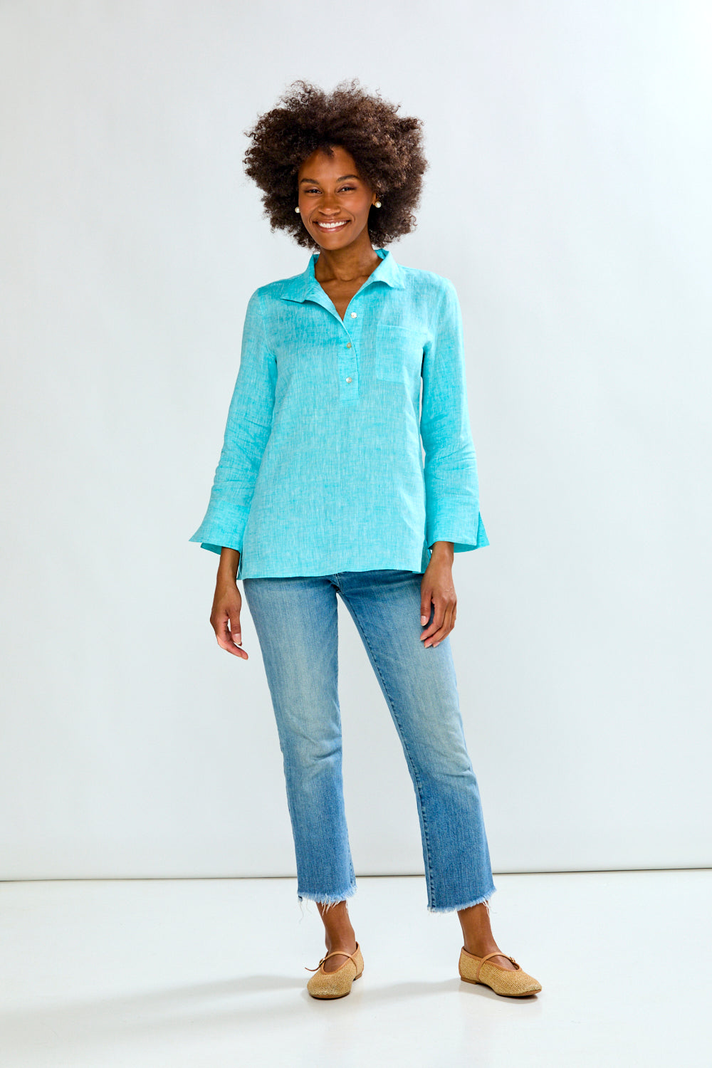 Woman wearing a light blue shirt and jeans against a white background