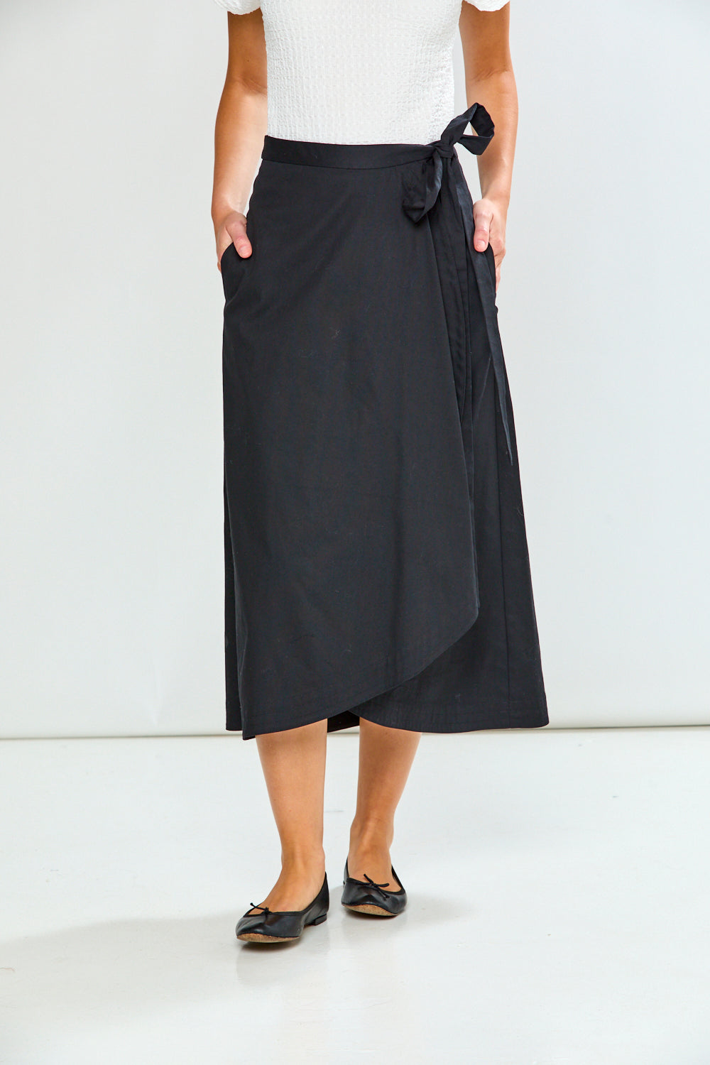 Person wearing a black wrap skirt on a white background