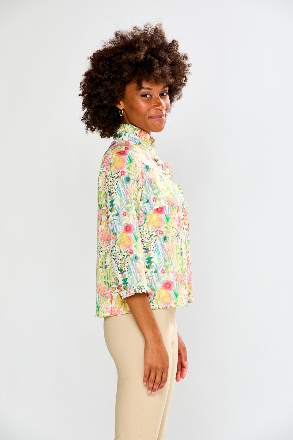 Woman wearing a colorful floral blouse against a white background