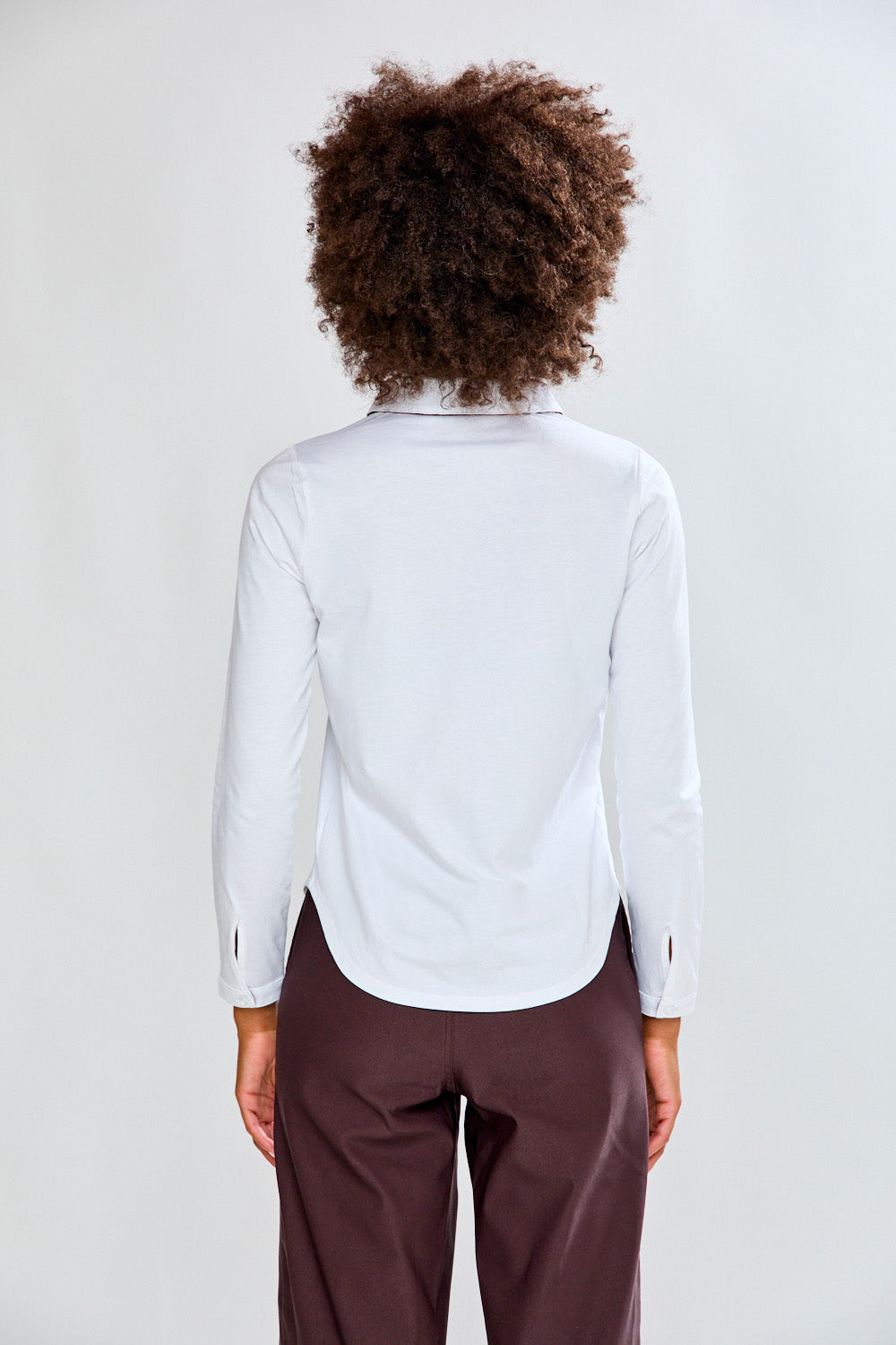 Woman wearing a white shirt and brown pants on a white background