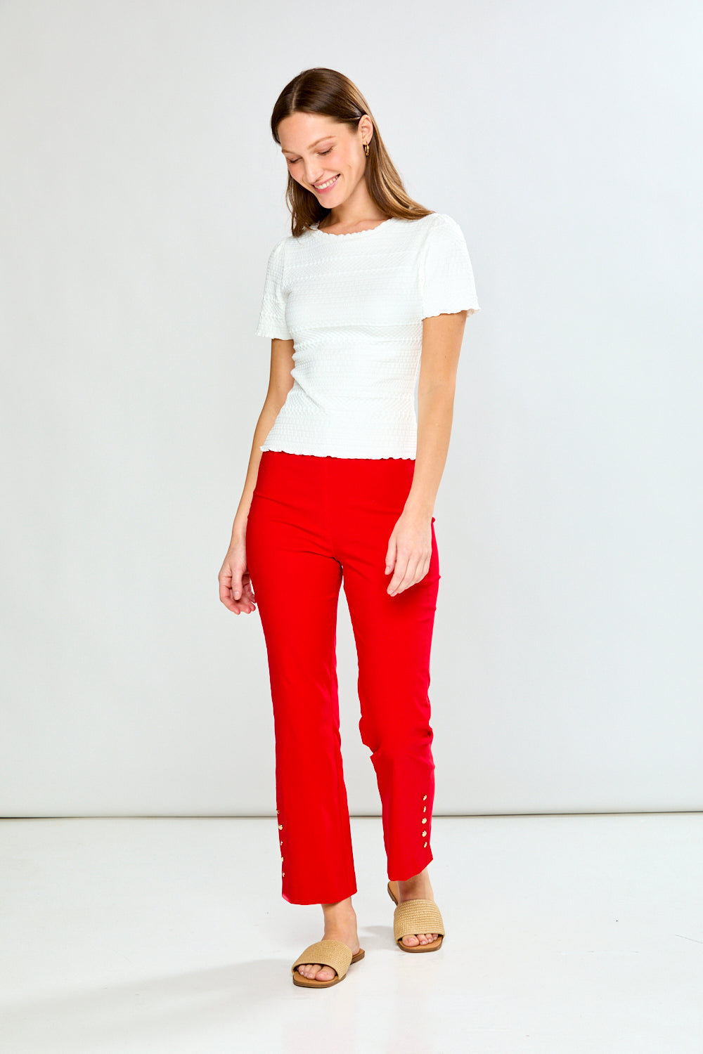 Woman wearing a white top and red pants on a white background