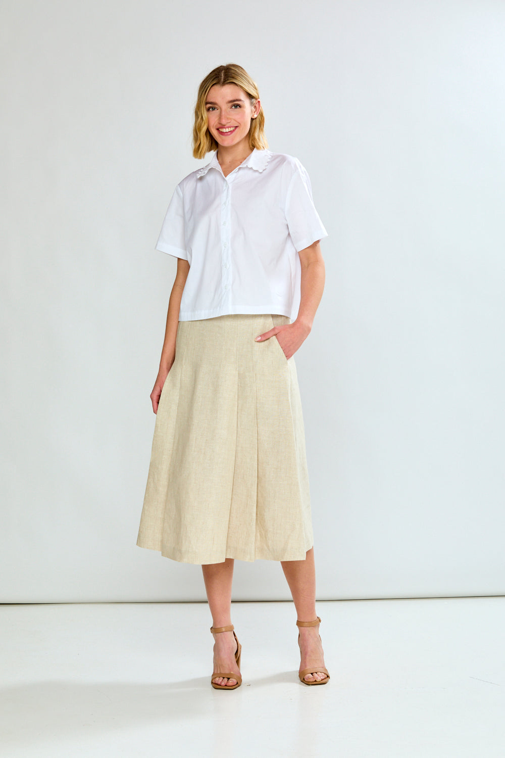 Woman wearing a white shirt and beige skirt on a white background