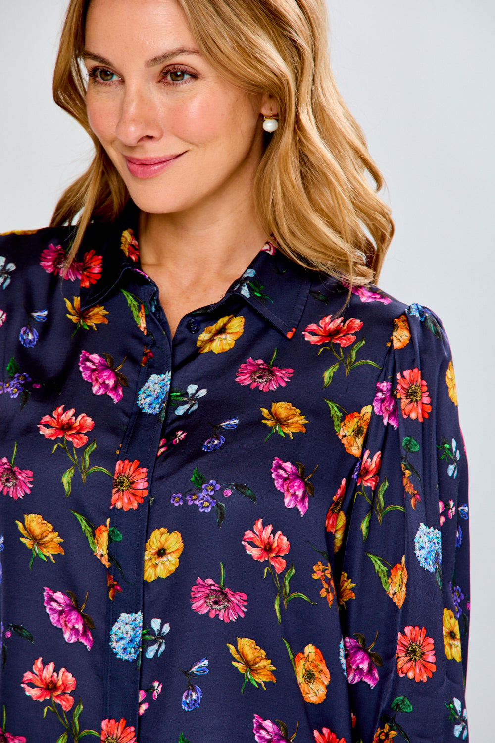 Woman wearing a navy floral blouse against a white background