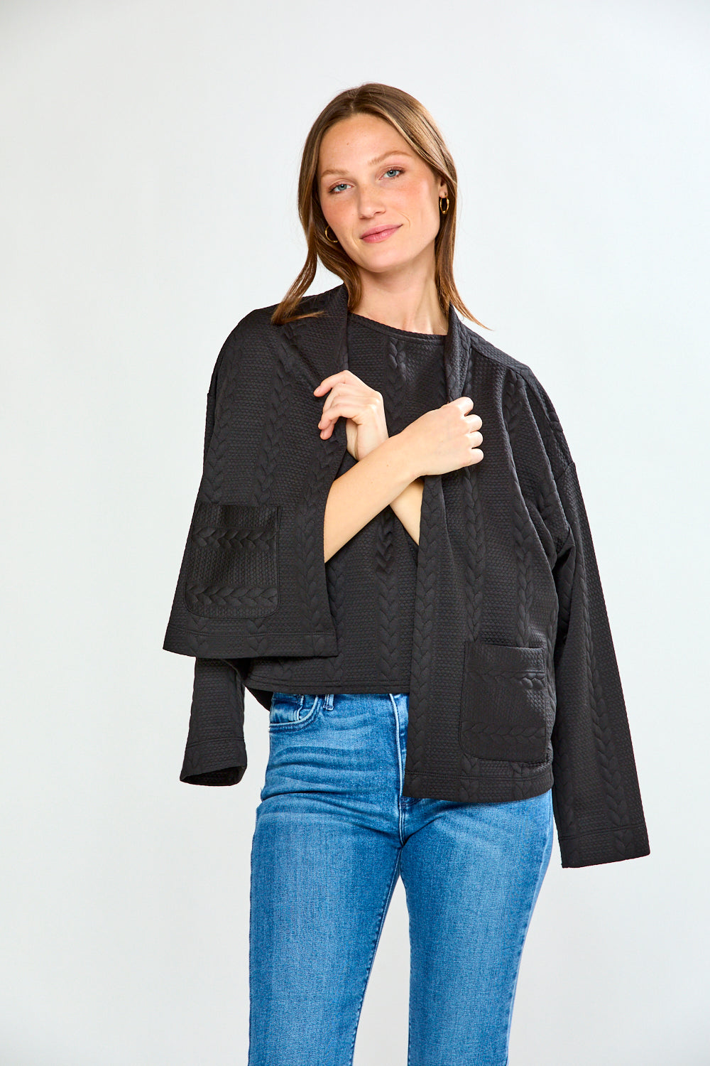 Woman wearing a black jacket and blue jeans on a white background