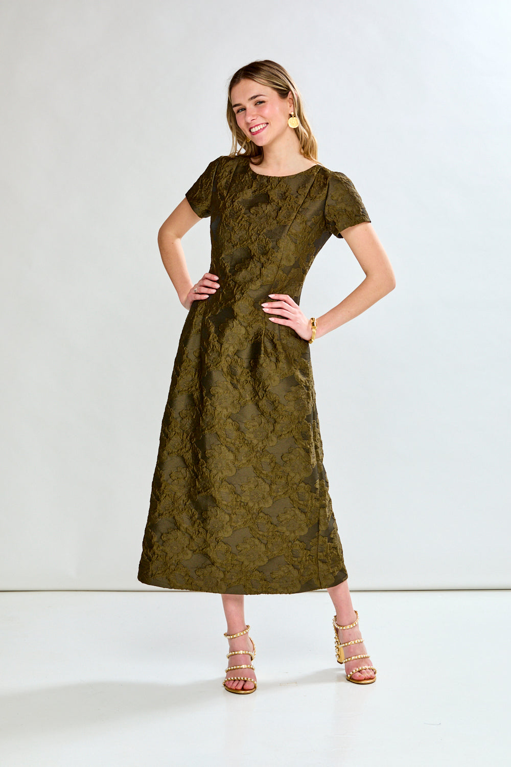 Woman wearing a green dress with a subtle pattern on a white background