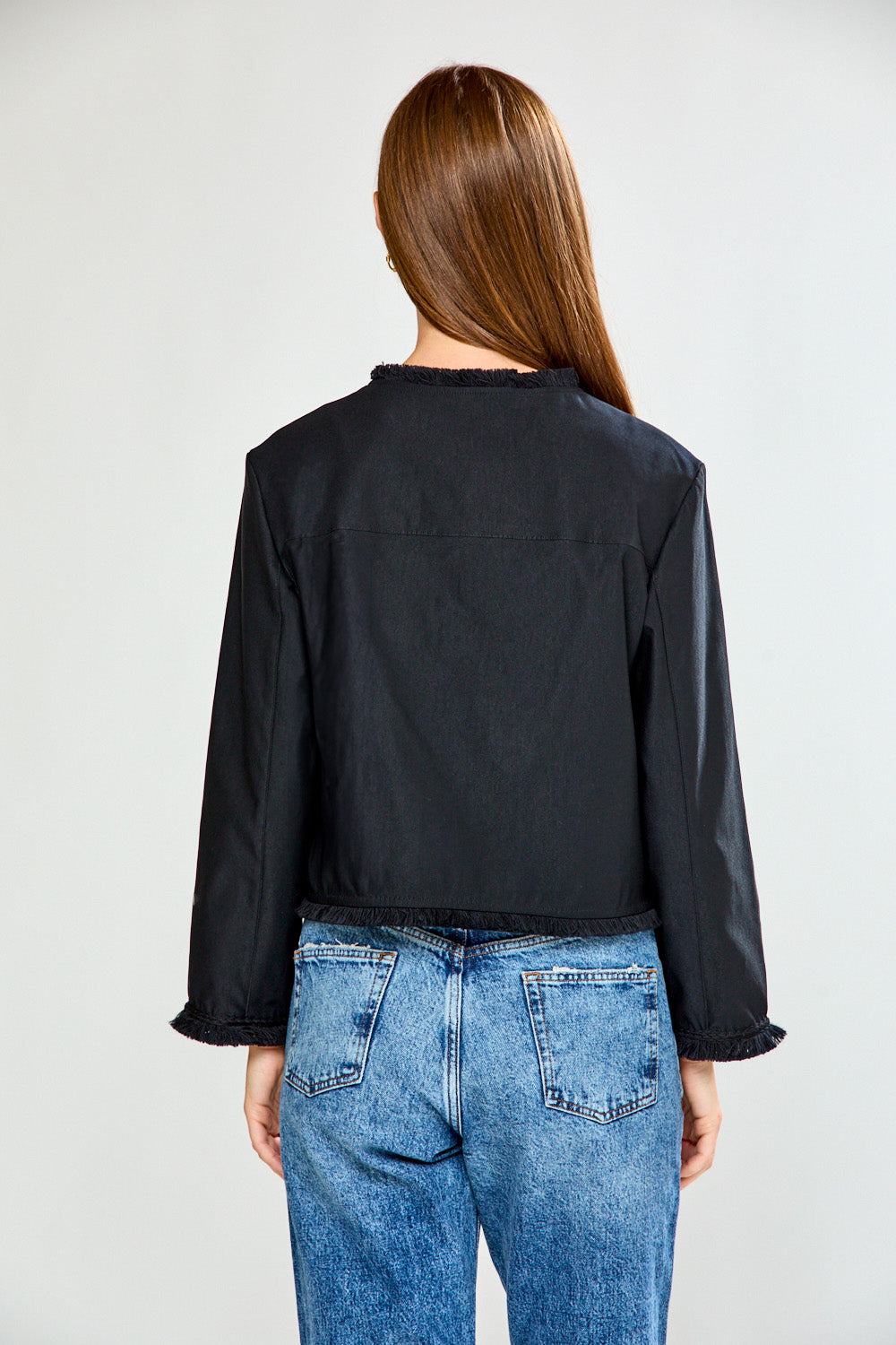 Woman wearing a black jacket and blue jeans on a white background