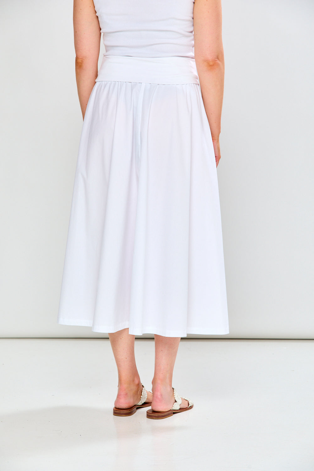 Person wearing a white dress standing against a plain background