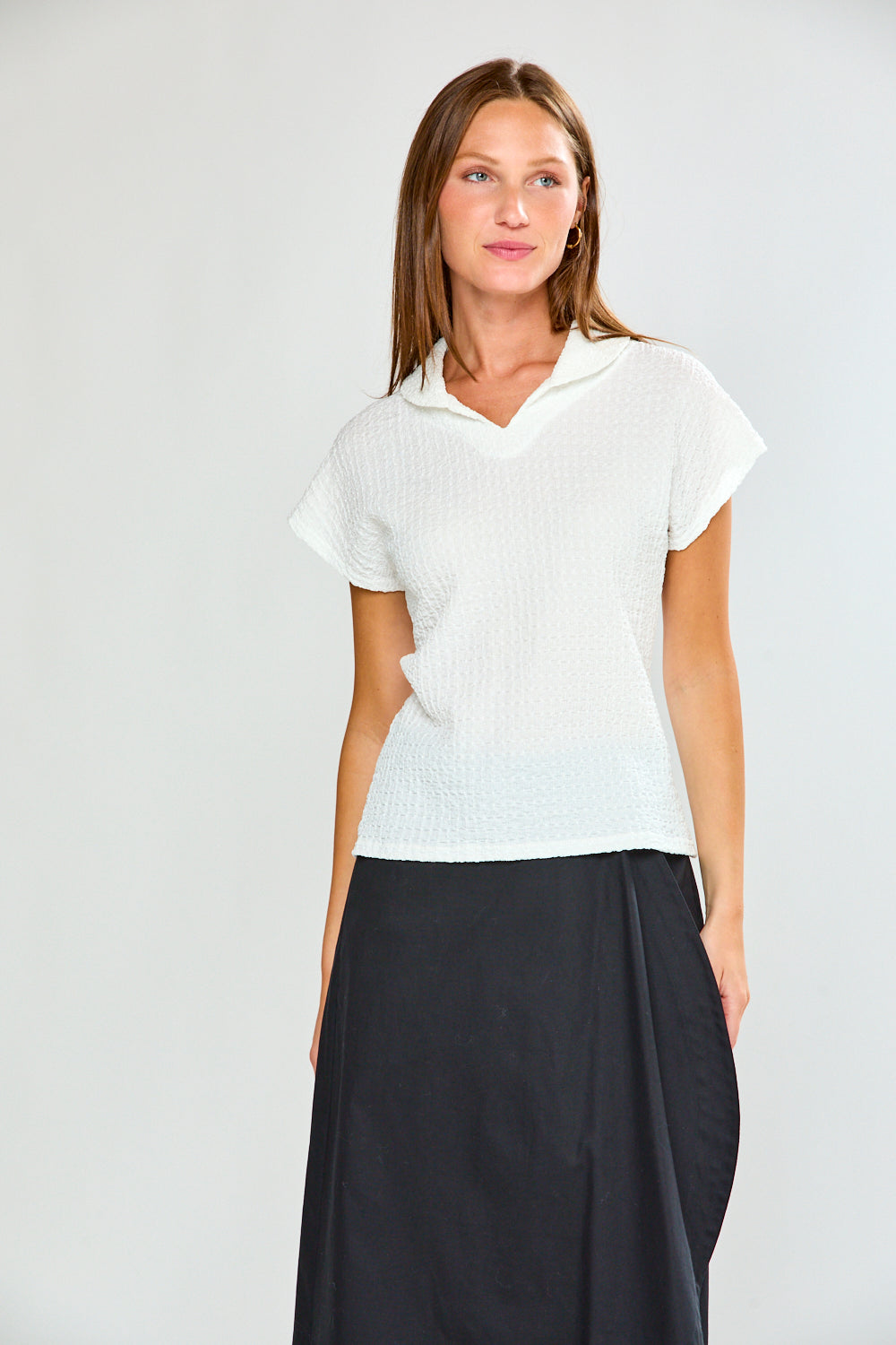 Woman wearing a white short-sleeve top and black skirt on a white background
