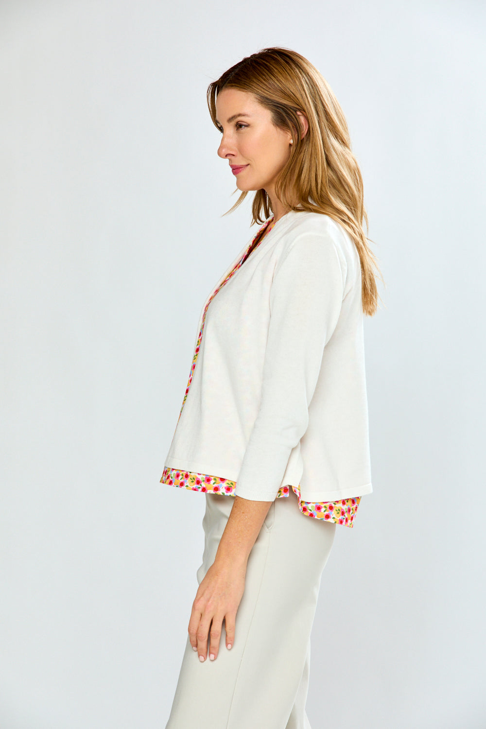 Woman wearing a white outfit with colorful trim on a plain background