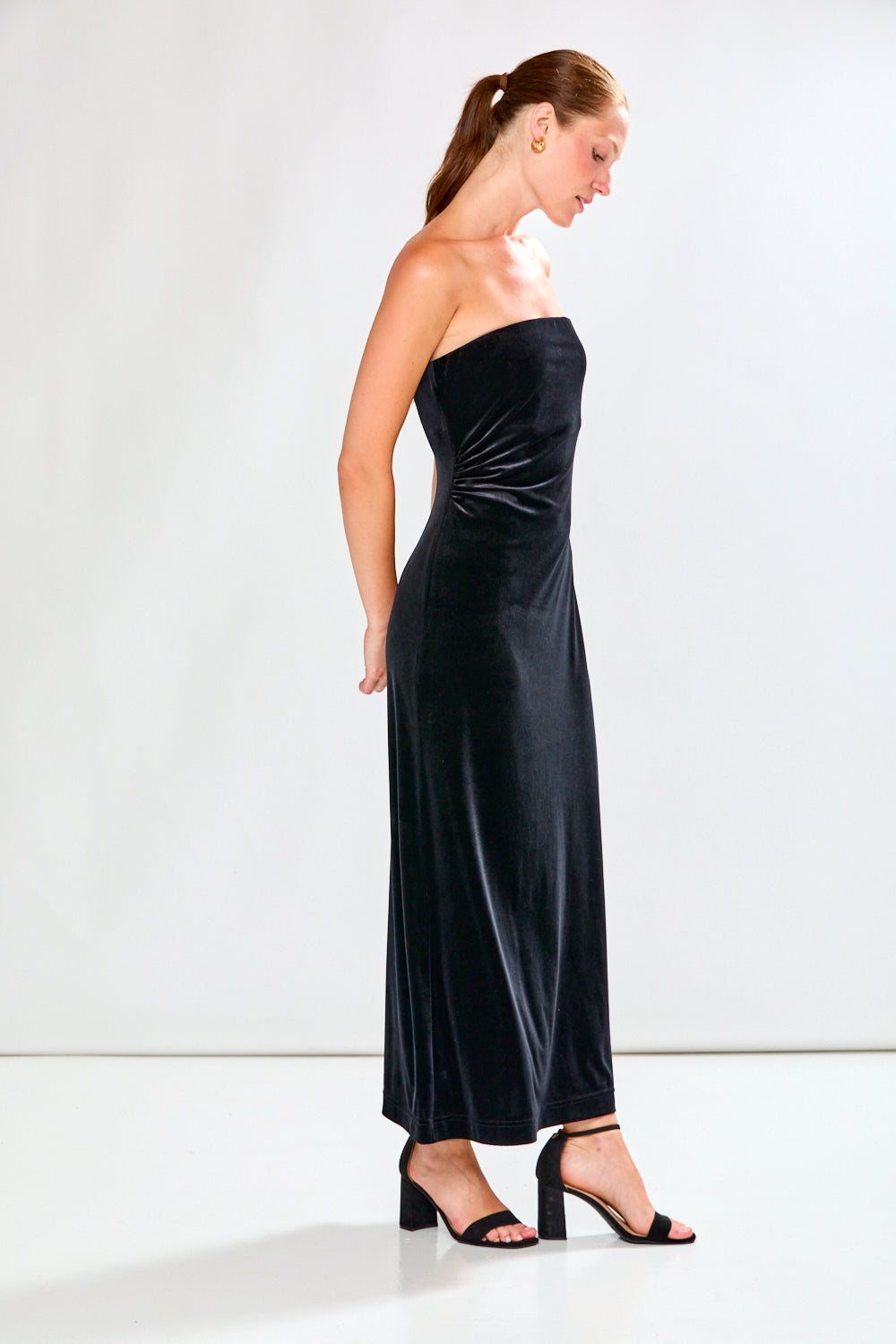 Woman wearing a black strapless dress against a white background