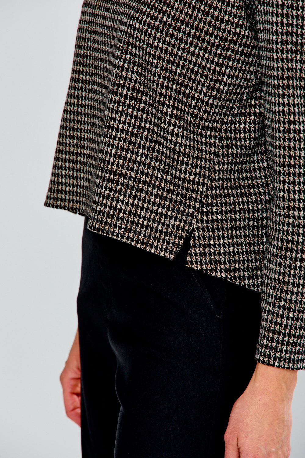 Woman wearing a plaid top with black pants on a light gray background