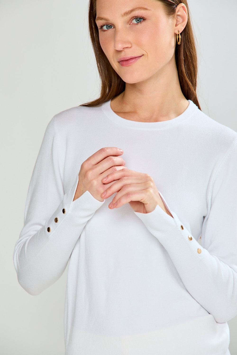 Woman wearing a white long-sleeve sweater and yellow pants on a light gray background